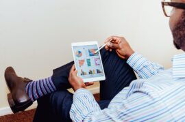 Man seated holding tablet showing graphs