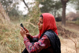 Indian woman in field using phone