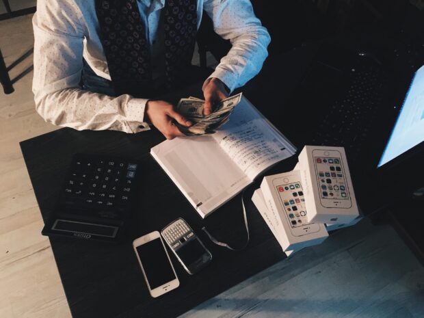 Man holding cash with book and calculator